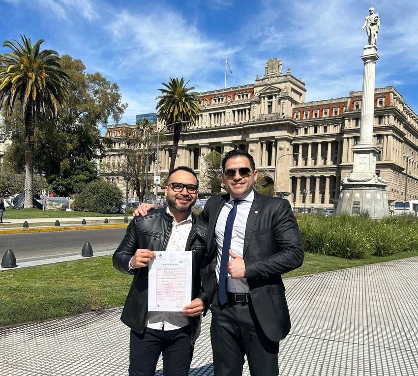 Dr. Portillo with a client and their Argentine certificate of naturalisation, in front of the Palacio de Tribunales